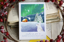 Lade das Bild in den Galerie-Viewer, Postkarte - Hase im Schnee - Polarlichter - Berglandschaft mit Hütte - warm and cozy holiday - Weihnachten Winter - Eigene Illustration