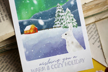 Lade das Bild in den Galerie-Viewer, Postkarte - Hase im Schnee - Polarlichter - Berglandschaft mit Hütte - warm and cozy holiday - Weihnachten Winter - Eigene Illustration